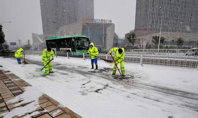 People clear accumulated snow to avoid traffic disruption in parts of China