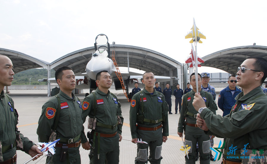 ↑舰载航空兵某部司令员戴明盟向飞行员演示空中飞行注意事项。